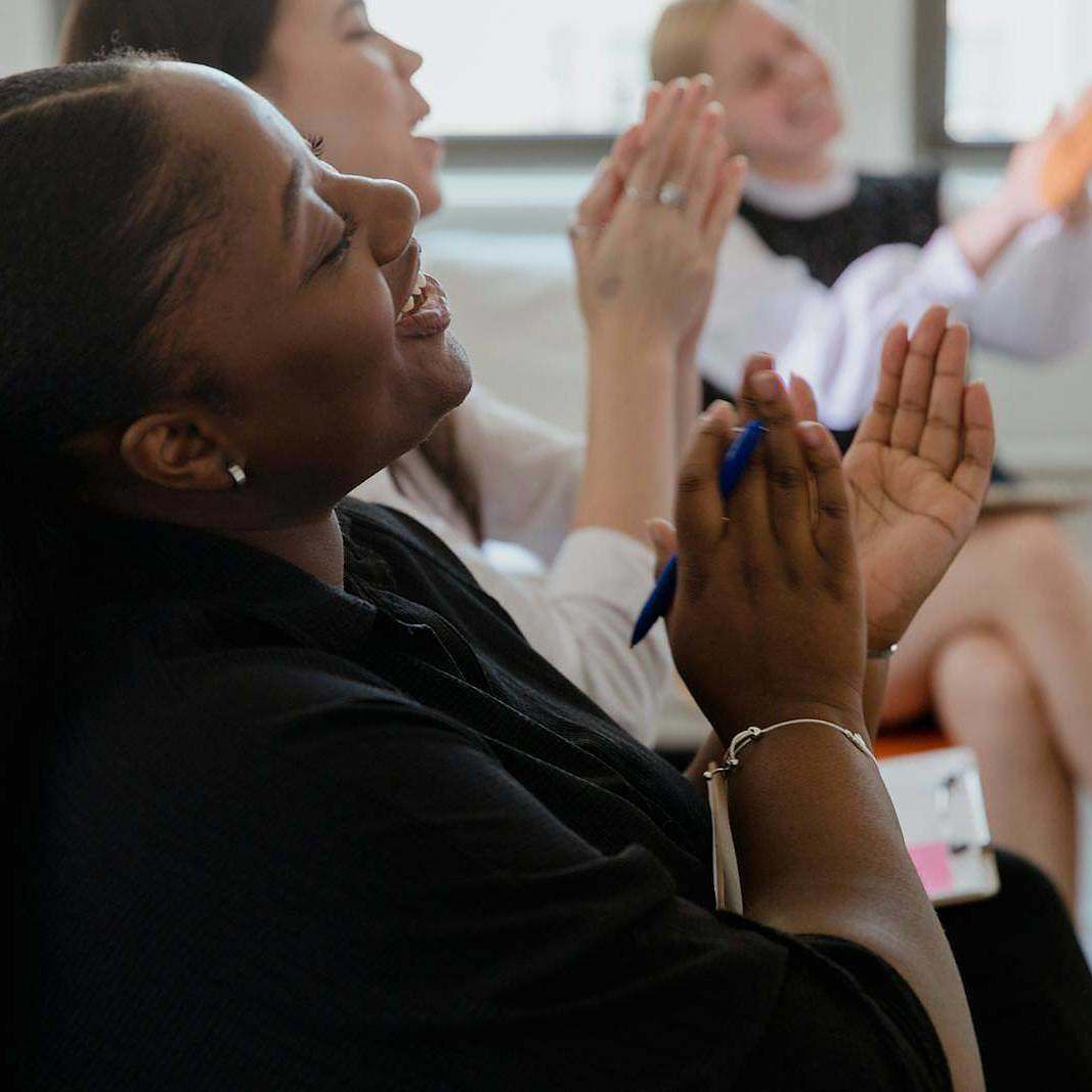 A diverse group of colleagues applauding during an indoor office meeting.