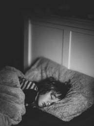 grayscale photography of kid lying on bed