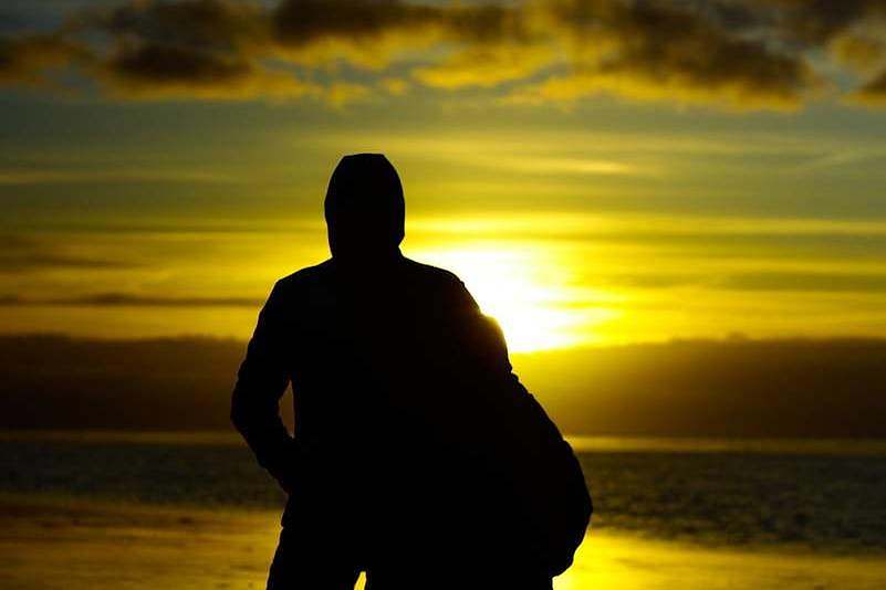silhouette photo of two persons standing beside beach