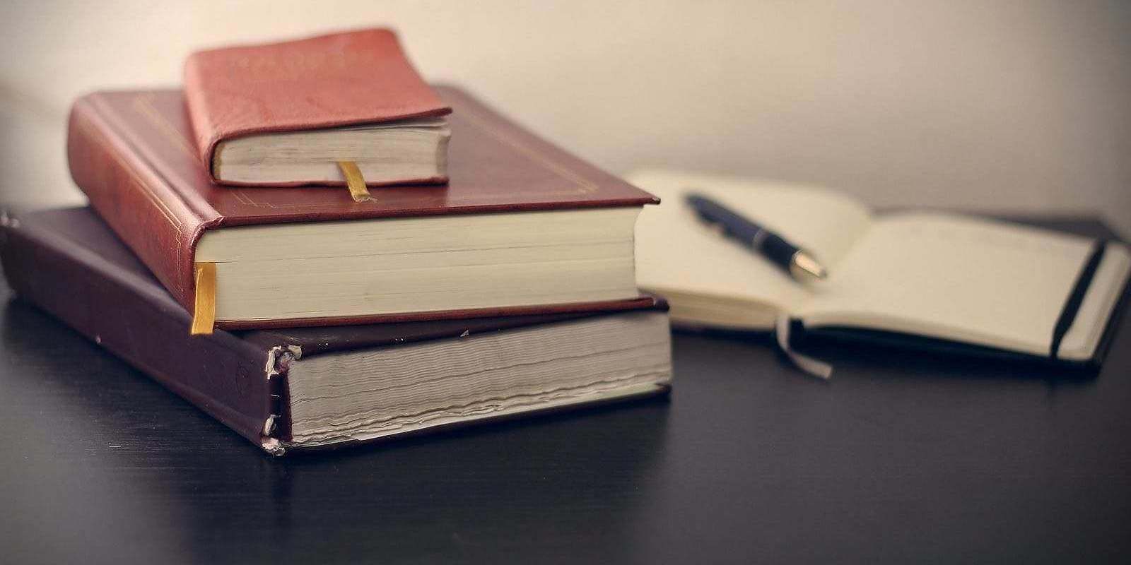 selective focus photography of three books beside opened notebook