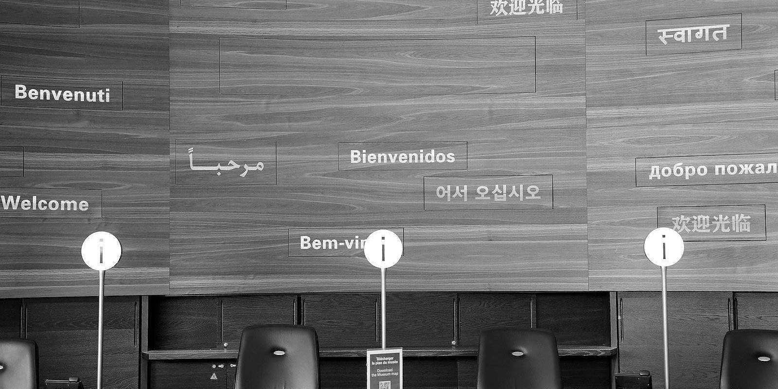 Welcome signs in multiple languages on wooden wall