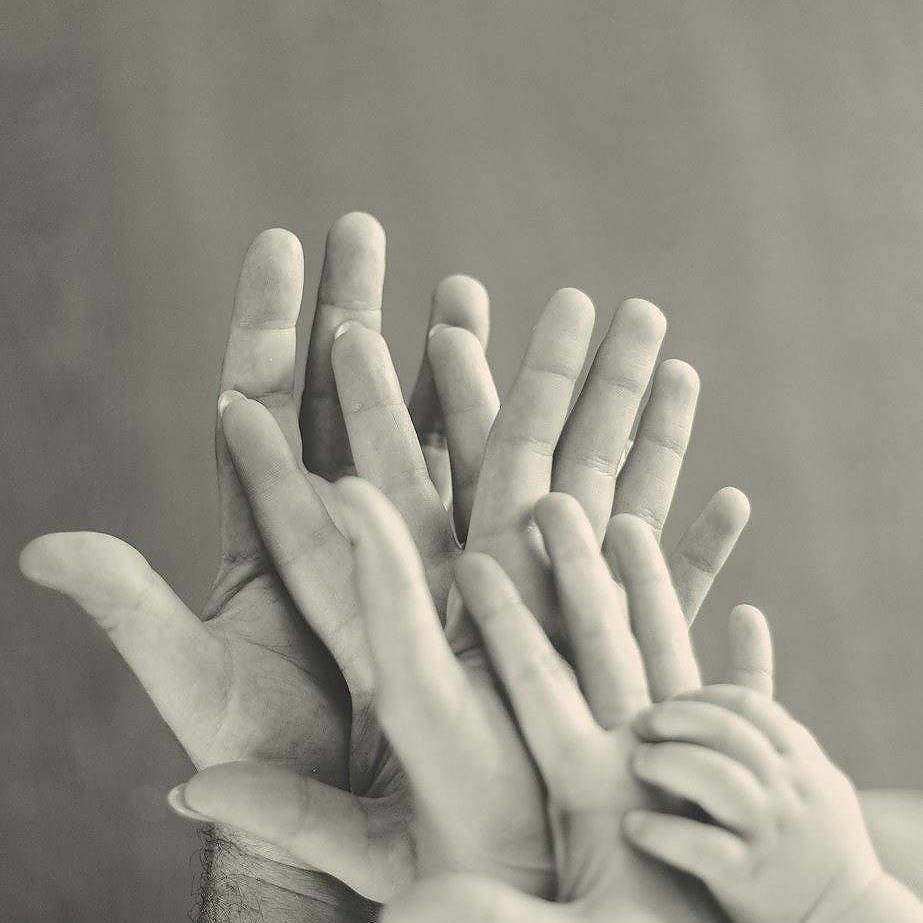 grayscale photo of family's hands